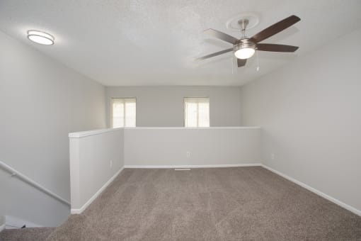 an empty living room with a ceiling fan and white walls