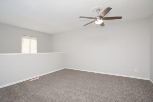 an empty living room with a ceiling fan