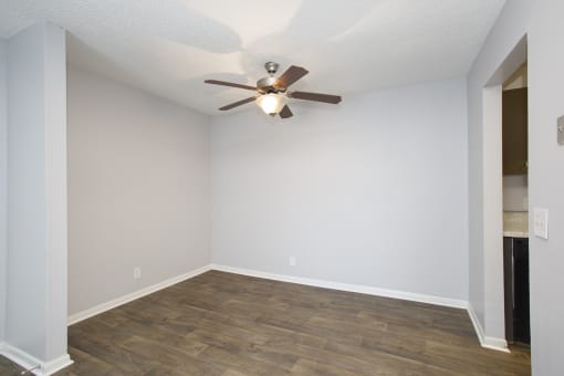 an empty living room with a ceiling fan and wood floors