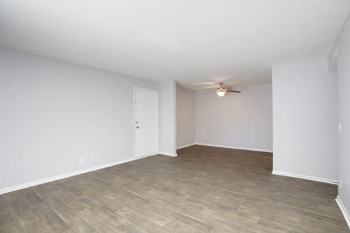 an empty living room with white walls and a ceiling fan