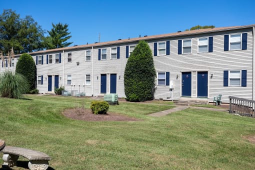 a large white building with blue doors and a grassy yard