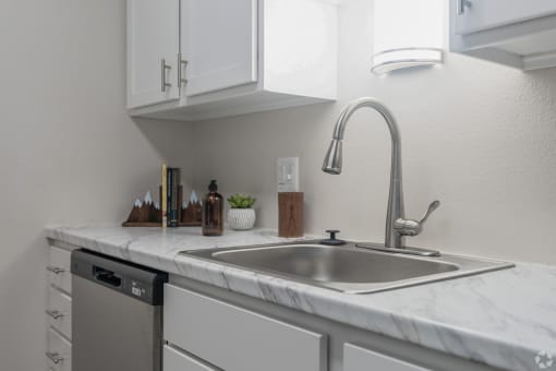 a kitchen with white cabinets and a stainless steel sink