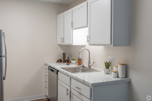 a kitchen with white cabinets and a stainless steel sink