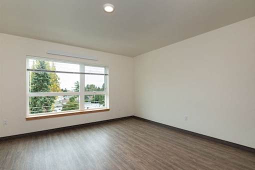 A room with a large window and wooden flooring.