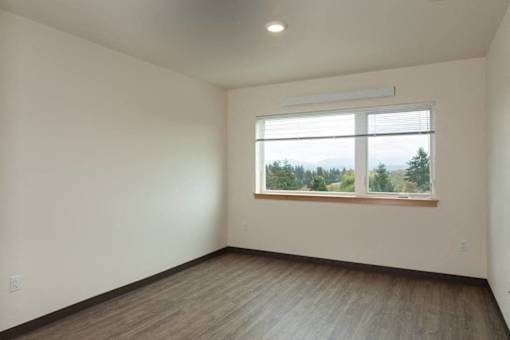 A room with a window overlooking a forest.
