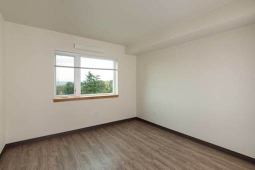 Empty room with a window and wooden floor.