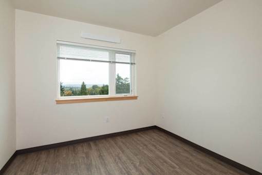 A room with a window and wooden flooring.