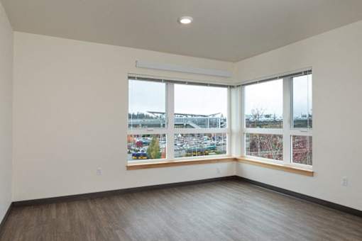 A large empty room with a view of a parking lot through the windows.