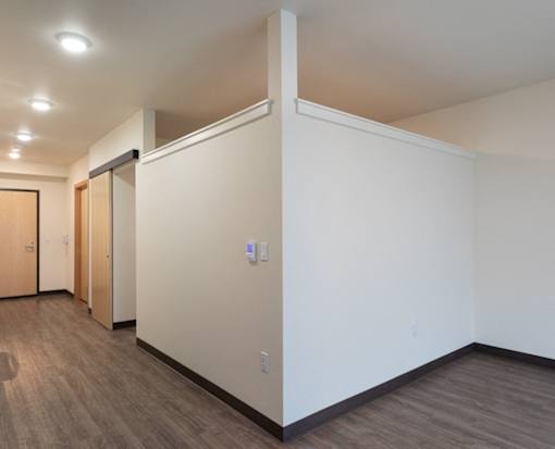 A room with a white wall and a brown floor.