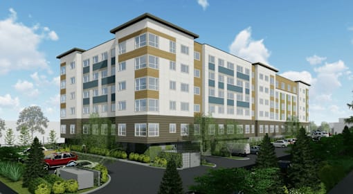 A modern multi-story building with a parking lot in front.