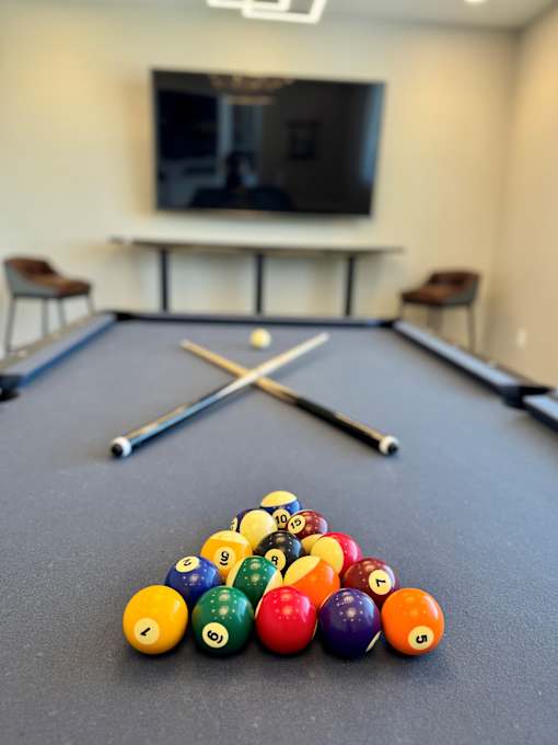 A pool table with a television in the background.