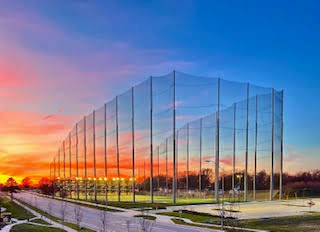 A long, tall, transparent fence stretches across a grassy field at Woodstone at Metro North Crossing Apartments, Kansas City, MO