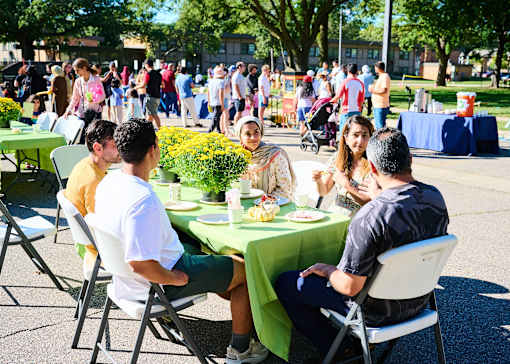 A group of people are sitting around a table outside on a sunny day.