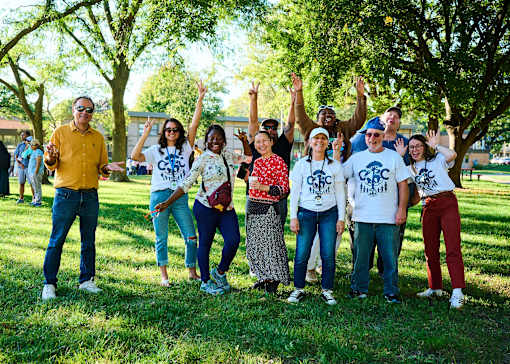 A group of people wearing white t-shirts with the text "CBC" are standing in a park.