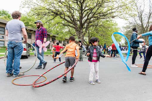 A group of people are playing with hula hoops in a street.