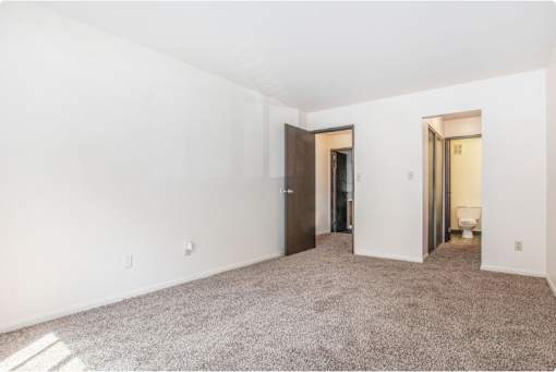 A room with a carpeted floor and two doors.