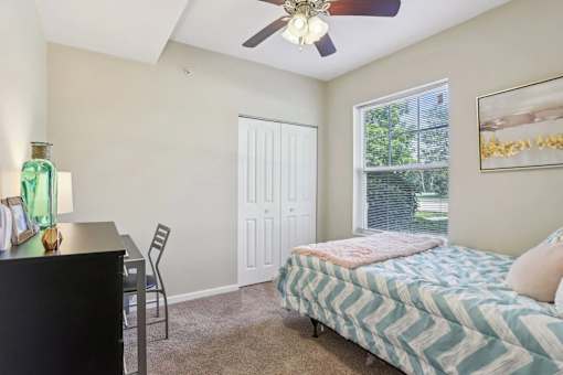 A bedroom with a bed, desk, and chair.