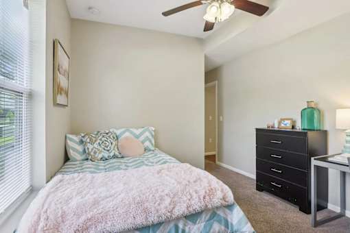 A bedroom with a bed, dresser, and window.