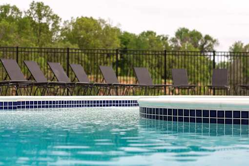A pool with a black fence and chairs.