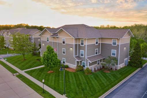 Apartment complex with a green lawn and trees.