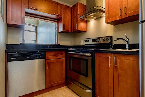 A kitchen with wooden cabinets and black countertops.