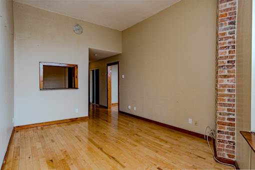 A room with wooden floors and a brick column on the wall.