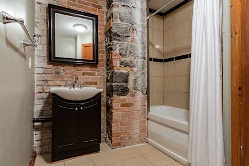 A bathroom with a stone wall and a white shower curtain.