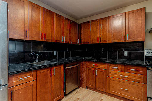 A kitchen with wooden cabinets and black countertops.