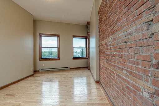 A room with a brick wall and wooden flooring.