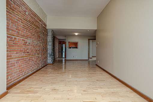 A long hallway with a brick wall on the left and wooden floors.
