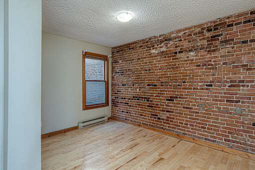A room with a brick wall and wooden flooring.