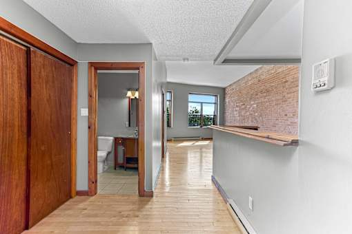 A long hallway with a doorway leading to a bathroom.