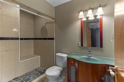 A bathroom with a toilet, sink, and mirror.