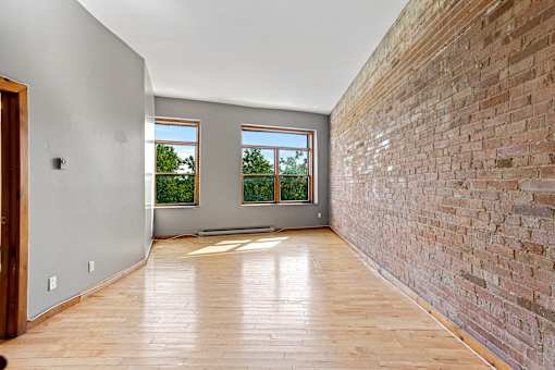 A room with wooden floors and a brick wall.