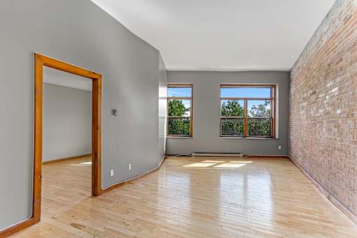 A room with wooden floors and a brick wall.