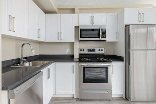A modern kitchen with white cabinets and stainless steel appliances.
