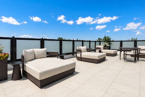 A patio with white furniture and a black railing.