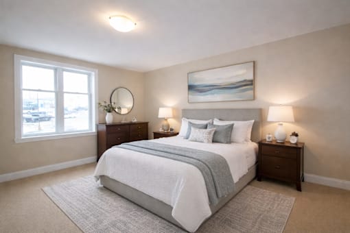 A bedroom with a large bed, two nightstands, and a painting on the wall.