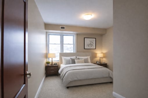 A bedroom with a large bed and two nightstands with lamps.