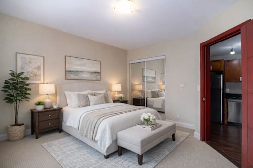 A bedroom with a large bed and a potted plant.