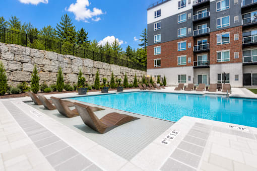 A swimming pool with lounge chairs and a building in the background.