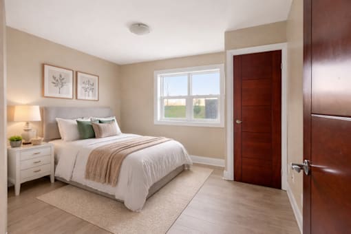 A bedroom with a bed, nightstand, and window.