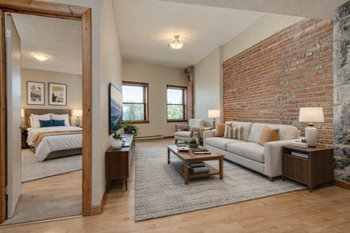 A living room with a white couch and a brick wall.
