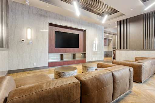 A modern living room with brown leather sofas and a flat screen TV at The Woods at 180 Kanata Avenue Apartments, Kanata, ON