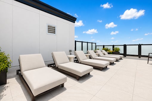 A row of white lounge chairs are arranged on a patio.