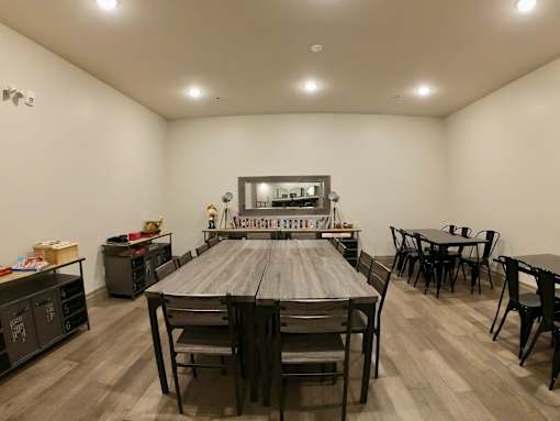 Creekside Common room large wooden table with chairs in a room with white walls and hardwood floors