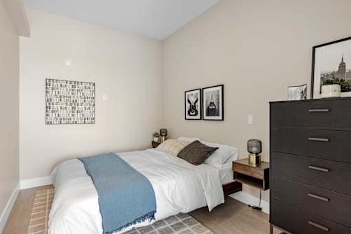 A bedroom with a white bed and a blue blanket at The Woods at 180 Kanata Avenue, Kanata, Ontario