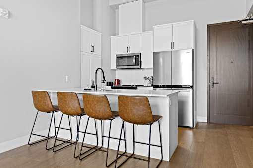 A kitchen with white cabinets and a brown bar stool.