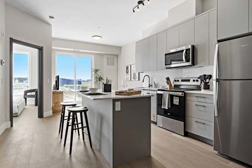 A modern kitchen with stainless steel appliances and a large island at The Woods at 180 Kanata Avenue Apartments, Kanata, ON K2T 0T4 