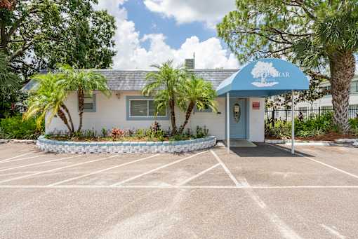 A small building with a blue awning is surrounded by a parking lot.